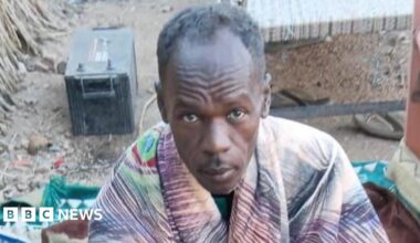 Mohamed Suleiman looks up at the camera, he has a blanket around his shoulders.