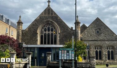 A church built with stone. There is a sign in front of the building.