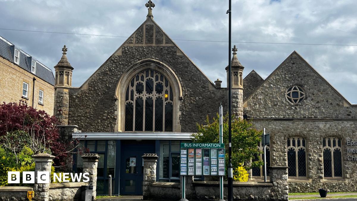 A church built with stone. There is a sign in front of the building.