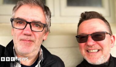 Stuart and Carl pose for a selfie. They both smile and are wearing glasses.