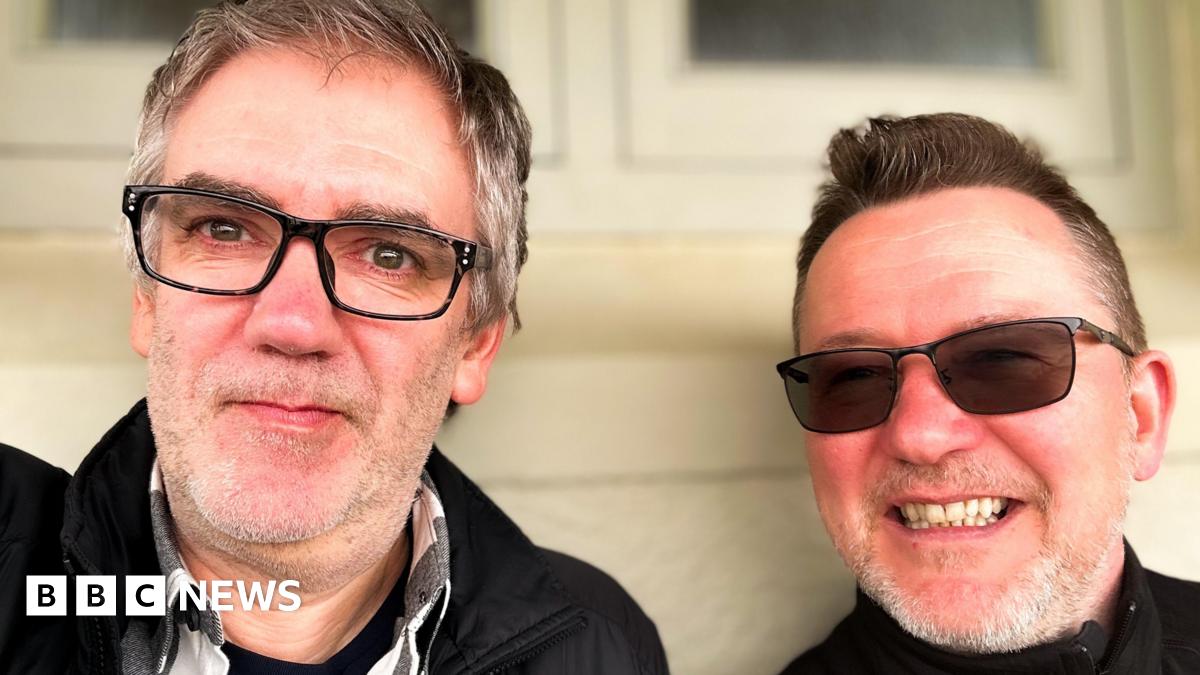 Stuart and Carl pose for a selfie. They both smile and are wearing glasses.