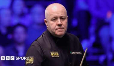 John Higgins holding a cue at the Tour Championship