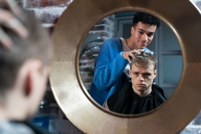 Oscar Branning having his hair washed by Josh Goodwin, seen through a hairdressing mirror in EastEnders.