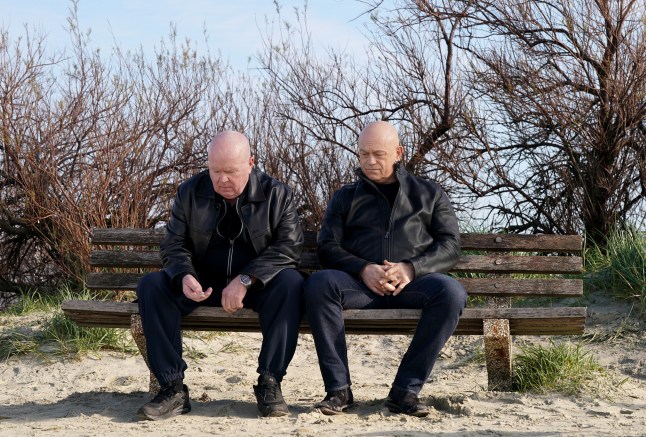 Phil and Grant Mitchell sat side by side on a bench in the sand