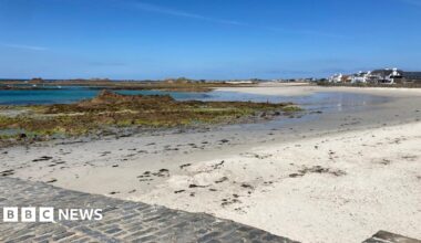 The picture shows Cobo beach on Guernsey's west coast on a sunny day with a blue sky