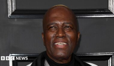 A close-up shot of Albert Mazibuko smiling with a black background behind him
