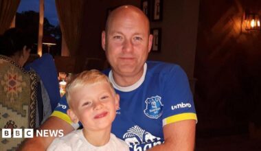 A man and boy smile at the camera