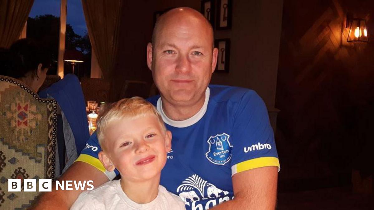 A man and boy smile at the camera