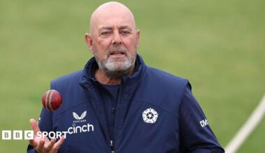 Darren Lehmann standing on a cricket pitch holding his right hand out ready to catch a cricket ball
