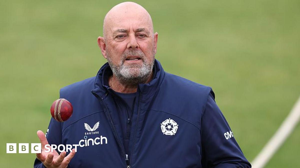 Darren Lehmann standing on a cricket pitch holding his right hand out ready to catch a cricket ball