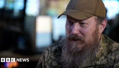 Unmanned Systems Forces commander Robert Brovdi, wearing a cap and with a long beard, is pictured speaking to the BBC