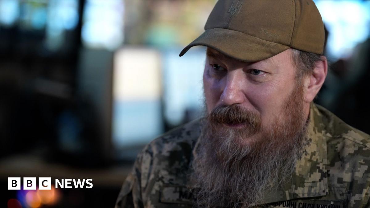 Unmanned Systems Forces commander Robert Brovdi, wearing a cap and with a long beard, is pictured speaking to the BBC