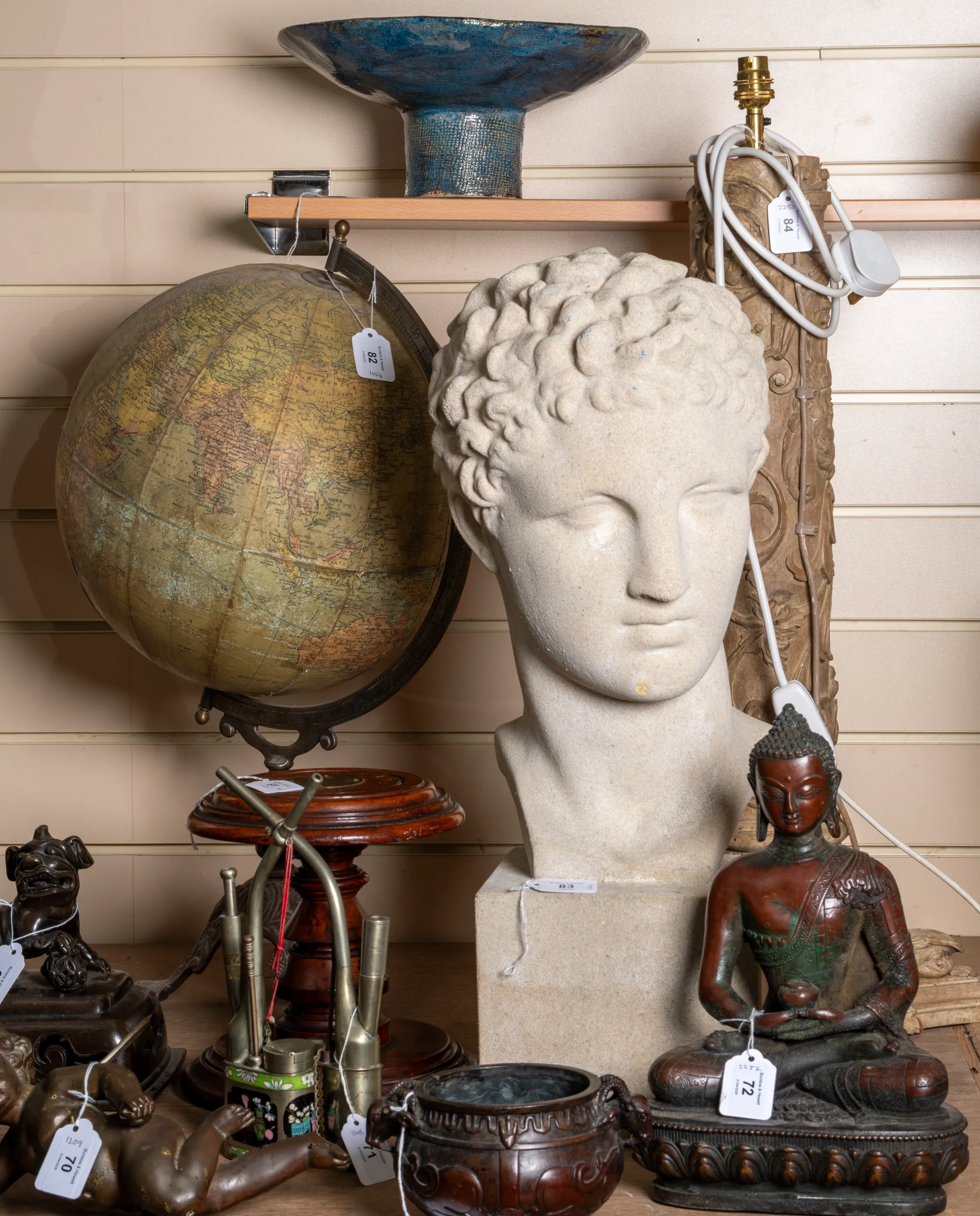 Items for sale at Burstow and Hewett Auction House, including an antique globe, a bust, and a Buddha statue.