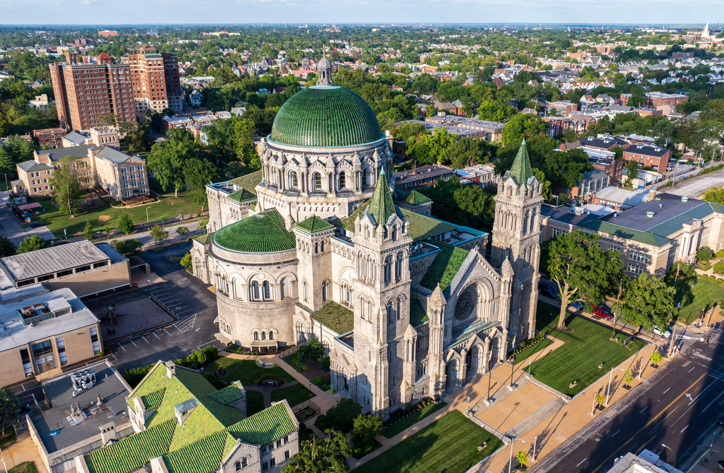 Aerial view of the Cathedral Basilica of Saint Louis with its large green dome, surrounded by buildings and trees.