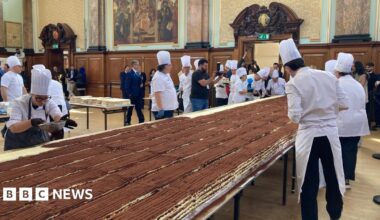Chefs work on a long tiramisu on a table