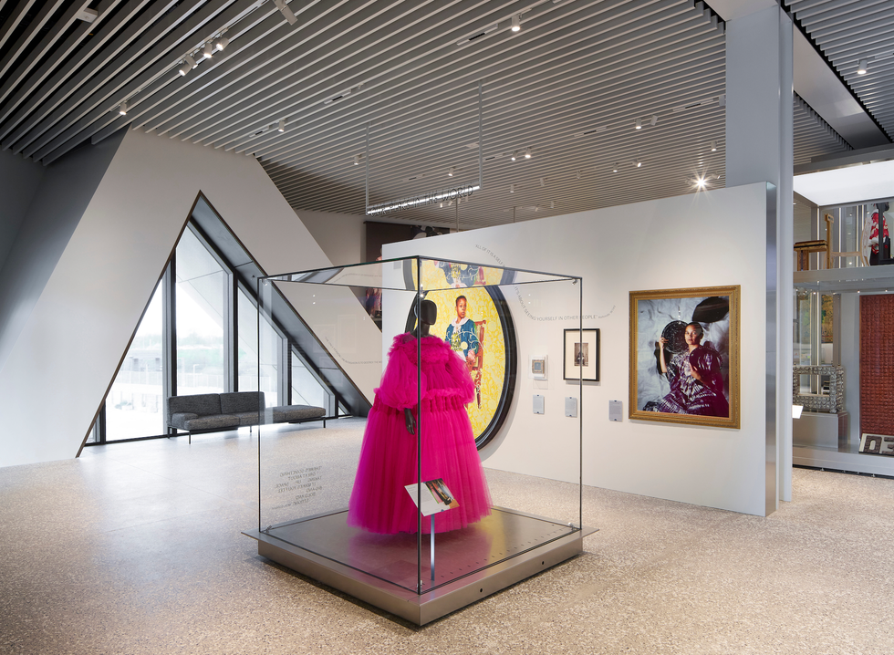 Fashion exhibit with a pink dress in a glass case.
