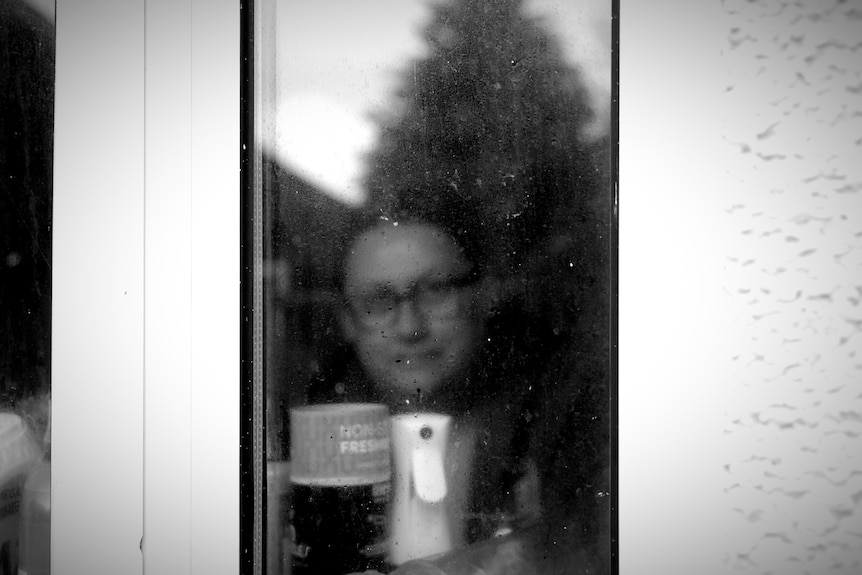 A woman, out of focus, through a window.