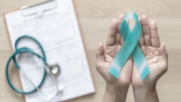 A pair of hands are raised, displaying a teal ribbon, with a stethoscope and a medical document in the background, symbolizing a