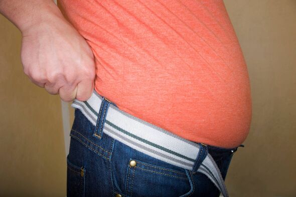 An individual dressed in an orange shirt and blue jeans is adjusting the belt around their waist, emphasizing the need for a pro