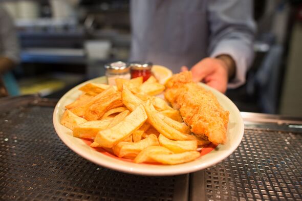 A chef poses with a plate of fish and chips A chef poses with a plate of fish and chips