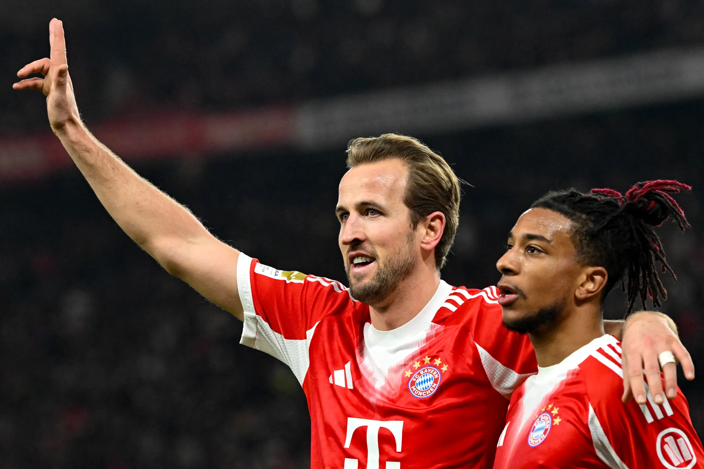 Harry Kane celebrating with Michael Olise after scoring a hat-trick for Bayern Munich.