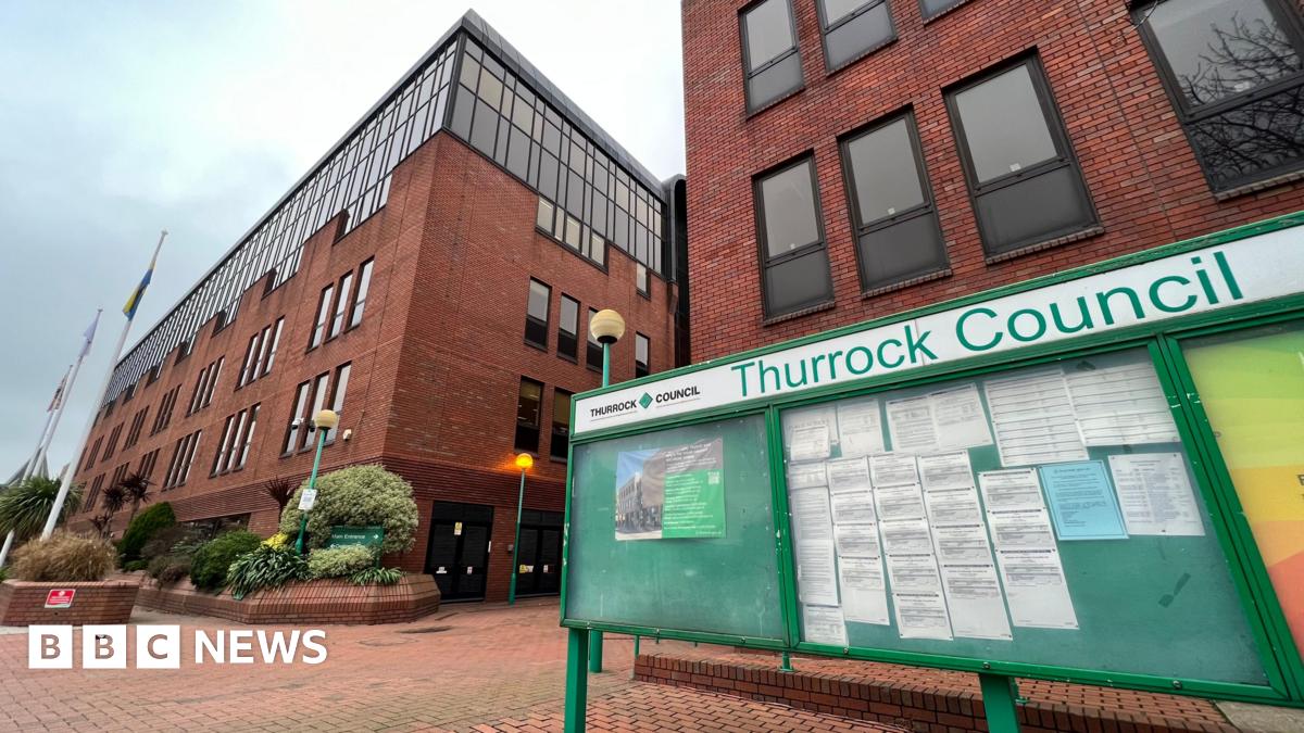 The outside of Thurrock Council's red brick offices. A green notice board with three panels stands in the foreground.