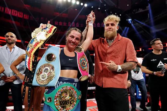 Ellie Scotney has her hand raised by Jake Paul in the ring
