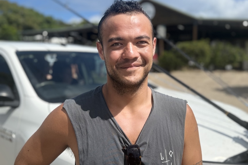 A man in a grey singlet smiling.