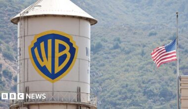 A water silo with the Warner Bros logo on it next to a US flag.
