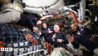 four astronauts floating in no gravity on spacecraft with gear all around them