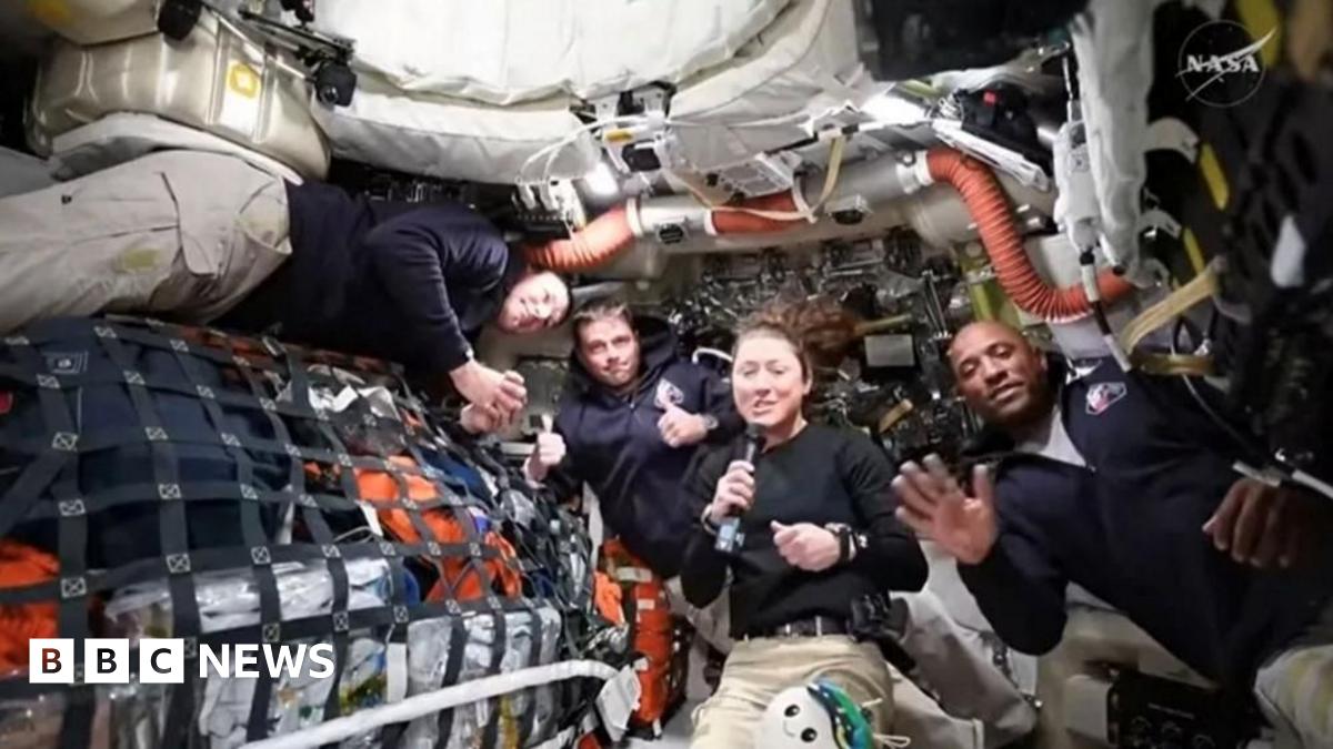 four astronauts floating in no gravity on spacecraft with gear all around them
