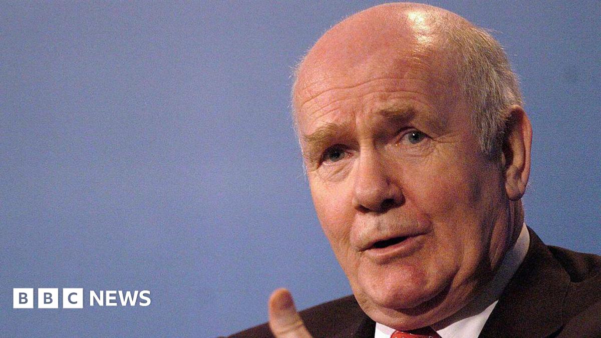 Close up shot of John Reid talking as he gestures with his hands.