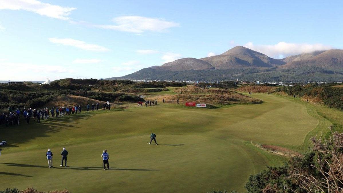 Golfers on the green at Royal County Down Golf Club. The Mourne Mountains can be seen in the distance.