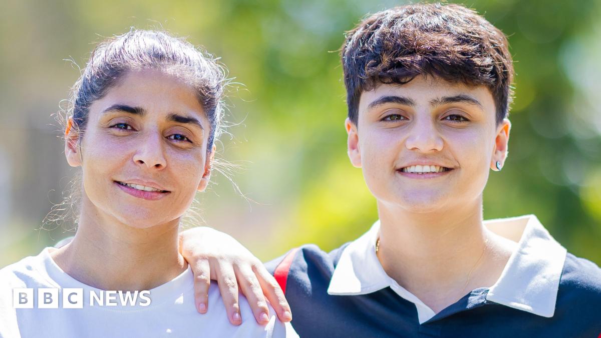 Atefeh Ramezanisadeh (L) and Fatemeh Pasandideh pose for a photo, blurred greenery in the background