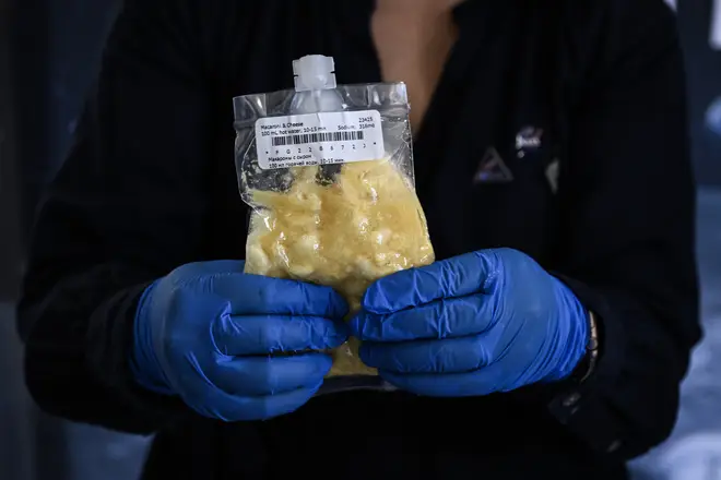 NASA space food scientist Xulei Wu holds a package of macaroni and cheese, part of the Artemis II crew's in-flight meals