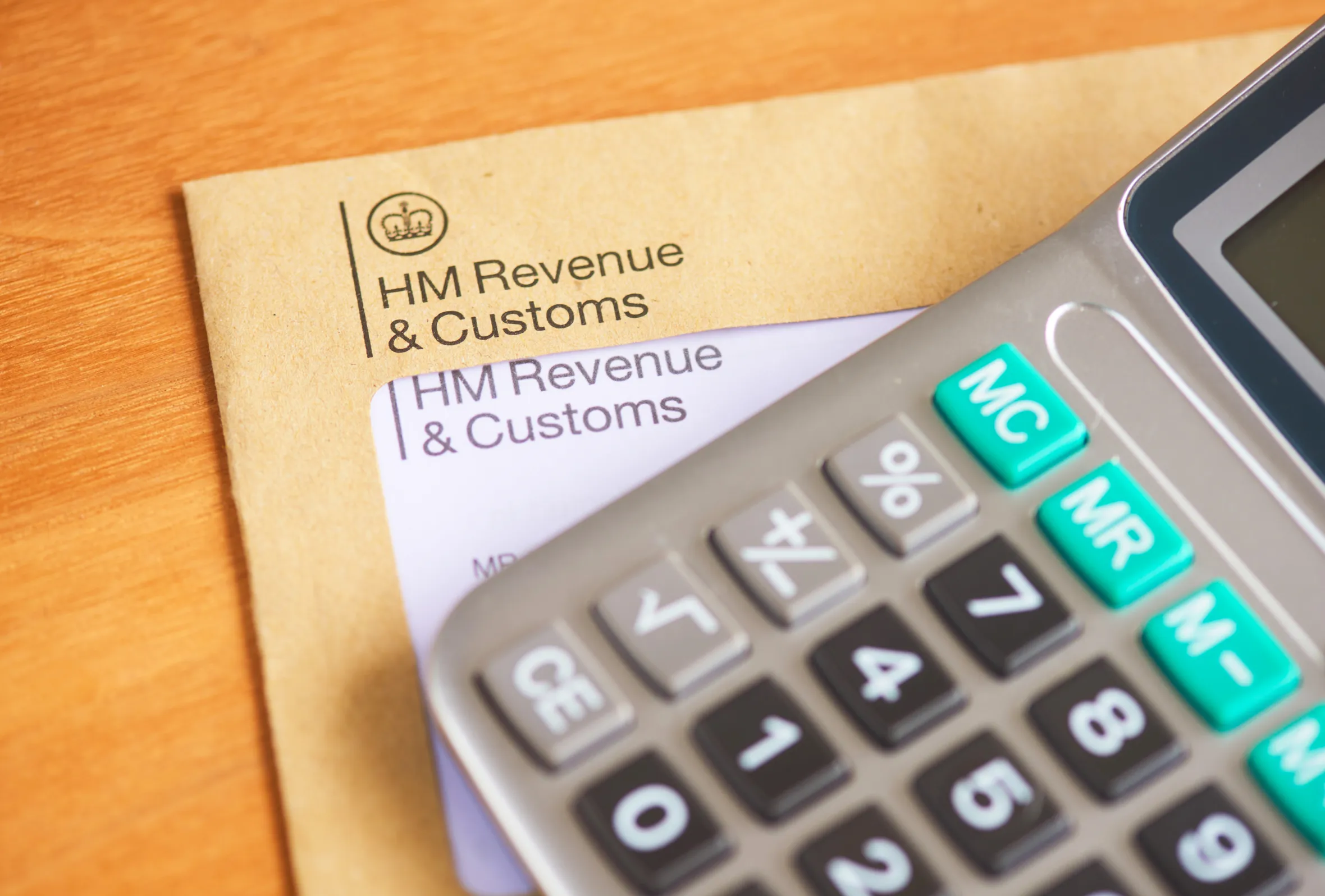 A close-up of a calculator on top of a "HM Revenue & Customs" envelope.