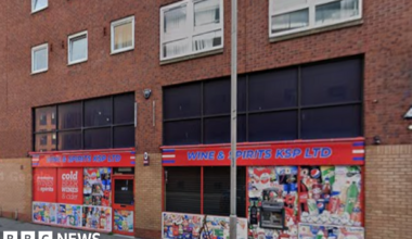 Exterior of Wines and Spirits KSP. It has red signage and multiple advertisements on the windows.