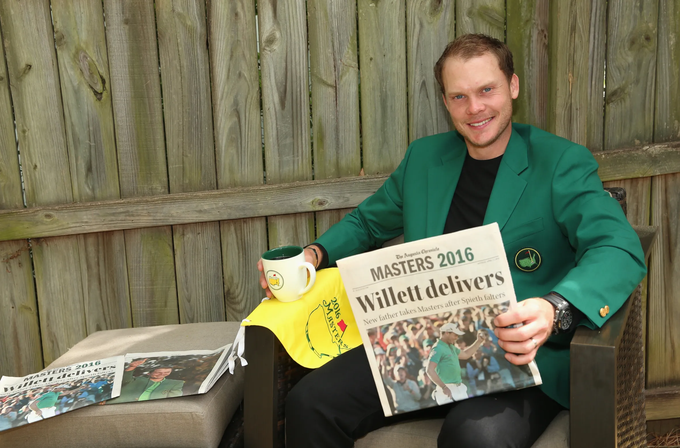 Danny Willett, 2016 Masters champion, sitting in a green jacket and holding a newspaper with the headline "Willett delivers".