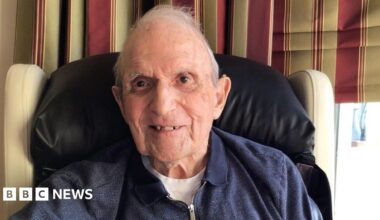 Rosemary Agnew, a woman with short grey hear, wearing a black top and pearl earrings and necklace.