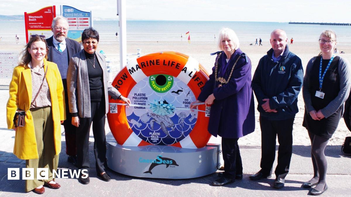 A group of six people standing either side of an installation shaped like a lifebuoy as they unveil the new unit