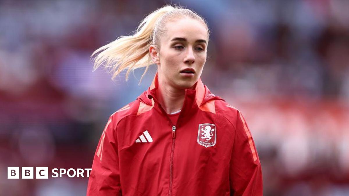 Missy Bo Kearns wearing a red jacket with an Aston Villa badge on the chest