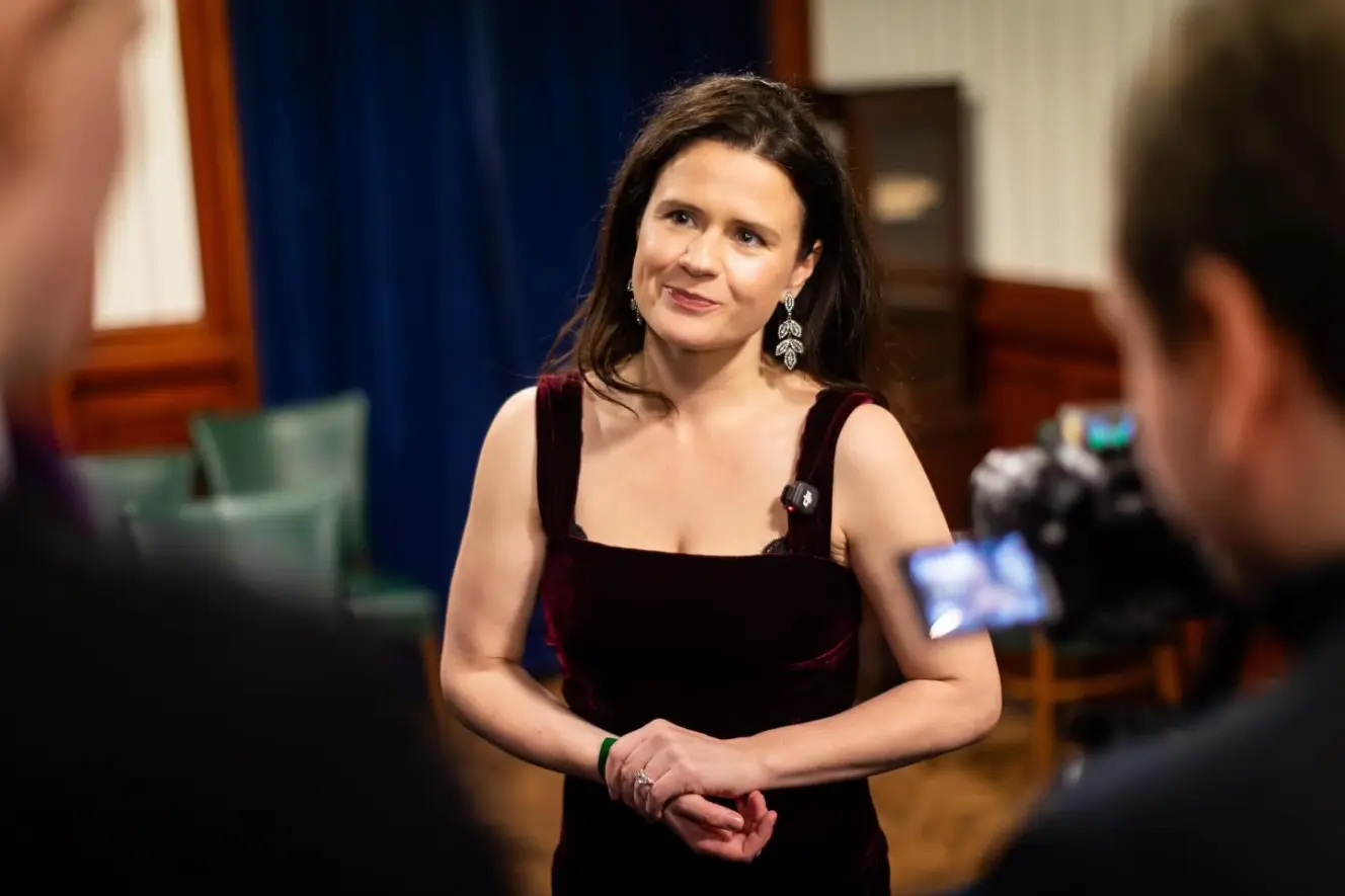 Joani Reid MP, a woman in a velvet dress, being filmed.