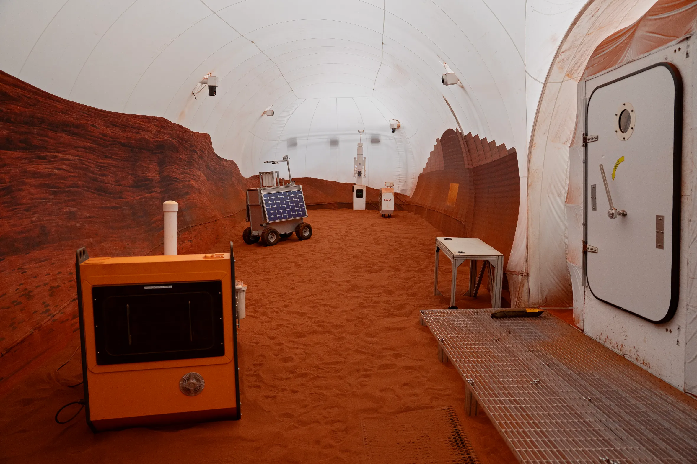 A simulated Mars habitat with red sand on the ground and rock formations against the walls.