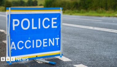 A blue police accident sign is placed in the carriageway of a road.