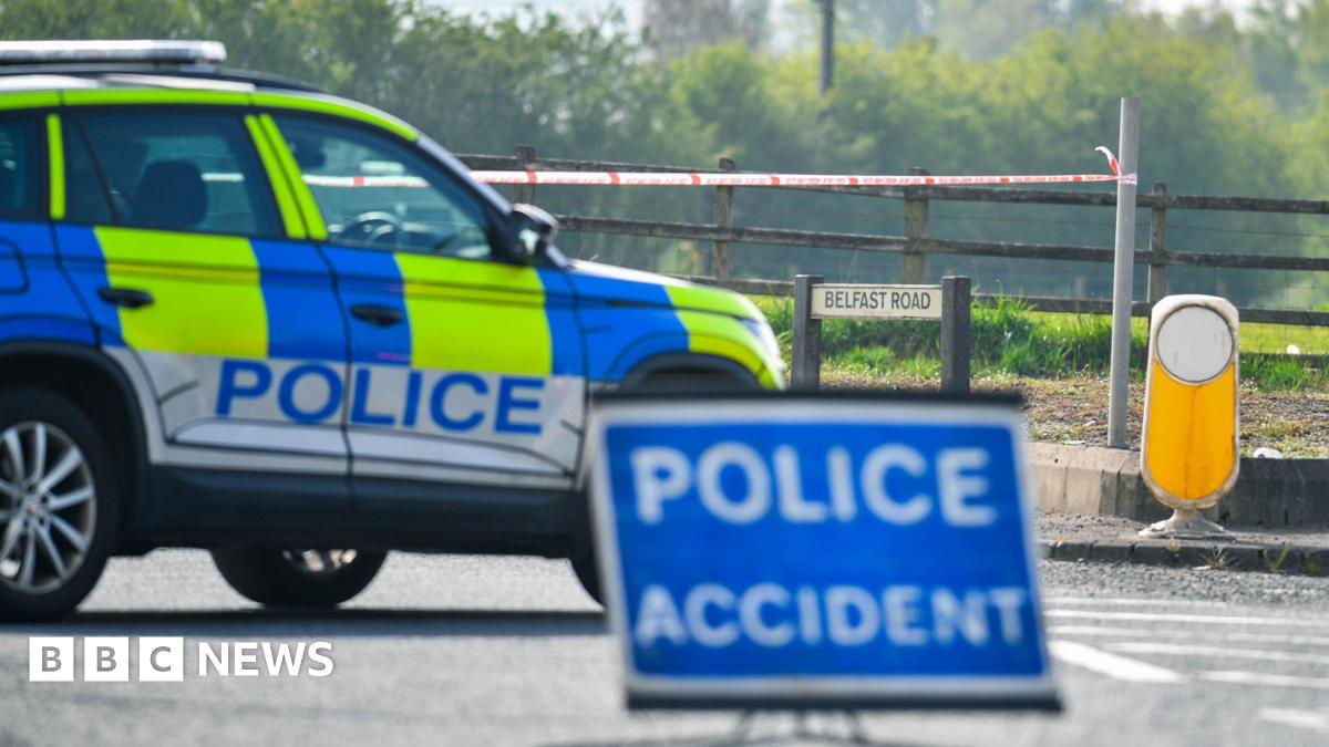 A yellow and blue police jeep parks across the road in front of a blue 'police accident' sign.