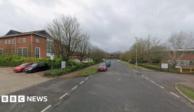 A view of Harvest Crescent on a cloudy day. A few cars are parked by the business units.