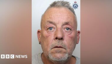 The mugshot of Gavin Shaw, who is wearing a grey t-shirt. He is starting forward and has short grey hair and a goatee.