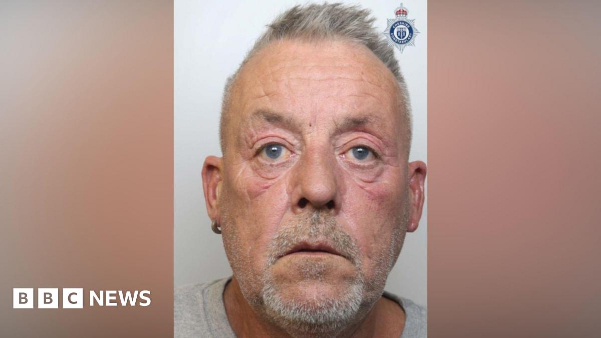 The mugshot of Gavin Shaw, who is wearing a grey t-shirt. He is starting forward and has short grey hair and a goatee.