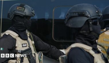 Two government forces personnel wearing all black and beige vests.