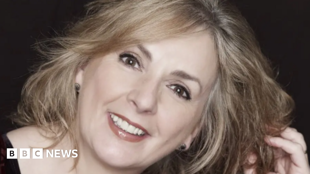 A close up image of Moya Brennan smiling at the camera. She has blonde hair and brown eyes.